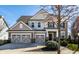 Charming two-story home with a three-car garage and beautifully landscaped front yard under a bright blue sky at 12729 Brandenburg Dr, Carmel, IN 46032
