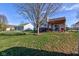 Green backyard with a fire pit and a pergola-covered deck area, ideal for outdoor enjoyment at 1360 Evergreen Dr, Greenfield, IN 46140