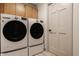 Laundry room features modern washer and dryer with upper cabinets and a laundry room door at 1448 Sedona Dr, Carmel, IN 46032