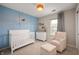 Bedroom with a white crib, dresser, neutral chair and ottoman, and light blue accent wall at 17918 Lucas Cir, Westfield, IN 46074