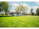 Quaint single-story house surrounded by a lush green lawn and mature trees at 1821 E Stop 10 Rd, Indianapolis, IN 46227