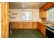 Functional kitchen with wood cabinets, green floors, and a window above the sink at 1821 E Stop 10 Rd, Indianapolis, IN 46227