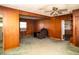 Cozy living room featuring wood paneling, green carpet, and a ceiling fan at 1821 E Stop 10 Rd, Indianapolis, IN 46227