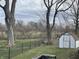 Spacious backyard featuring a chain-link fence, storage shed, mature trees, and plenty of green space at 1835 Carpenter Cir, Indianapolis, IN 46203