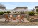 This backyard features a patio with wooden chairs, a fire pit, retaining wall, and partial lake views at 1975 Westminster Pl, Columbus, IN 47201