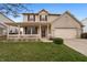 Charming home featuring a covered porch, brick details, well-maintained lawn, and an attached two-car garage at 1975 Westminster Pl, Columbus, IN 47201