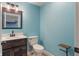 New half bathroom with modern dark wood vanity, decorative mirror, white toilet and turquoise walls at 2091 Banburry Pl, Avon, IN 46123