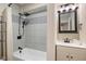 Bathroom features tiled tub with shower head, black fixtures, and a white sink vanity, creating a modern aesthetic at 2155 S Delaware St, Indianapolis, IN 46225