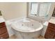 Cozy bathroom showing a white soaking tub with marble trim beside a window at 4703 River Ridge Dr, Indianapolis, IN 46240