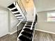 Modern entryway with black and white staircase, light gray walls, and a clear view of the front door at 5608 Lunsford Dr, Indianapolis, IN 46237