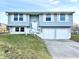 Light blue two-story home featuring shuttered windows, a two-car garage, and a staircase to the front door at 5608 Lunsford Dr, Indianapolis, IN 46237