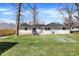 Spacious backyard with lush green grass, mature trees, and patio seating area at 5887 Meadowlark Dr, Indianapolis, IN 46226