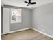 This bedroom has light gray walls, light-colored wood floors, white trim, a window, and a ceiling fan at 5887 Meadowlark Dr, Indianapolis, IN 46226