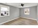 This bedroom has light gray walls, light-colored wood floors, white trim, and two windows at 5887 Meadowlark Dr, Indianapolis, IN 46226
