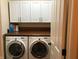 Functional laundry room with washer, dryer, overhead cabinets, and wood counter at 7336 Hardin Oak Dr, Noblesville, IN 46062