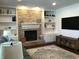 This living room features a brick fireplace, built-in shelves, modern decor, and a large TV at 7336 Hardin Oak Dr, Noblesville, IN 46062