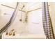 Bathroom featuring a white corner soaking tub with gold fixtures, shower, and gray striped shower curtain at 9619 E Southport Rd, Indianapolis, IN 46259