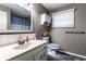 Well-lit bathroom with a vanity, beige countertops, decorated toilet, and a window with blinds at 9619 E Southport Rd, Indianapolis, IN 46259