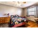 Comfortable bedroom featuring a ceiling fan, wood floor, and a colorful comforter and window treatment at 9619 E Southport Rd, Indianapolis, IN 46259