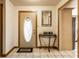 Inviting foyer with tile flooring, decorative mirror, console table, and an oval-glass front door at 9619 E Southport Rd, Indianapolis, IN 46259