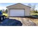 A standard detached garage with a white garage door and a cracked blacktop driveway in front of it at 9619 E Southport Rd, Indianapolis, IN 46259