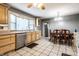 Eat-in kitchen featuring tile floors, oak cabinets, stainless steel dishwasher, and a big window at 9619 E Southport Rd, Indianapolis, IN 46259