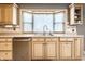 Bright kitchen with custom cabinetry, stainless steel dishwasher, and a bay window overlooking the sink at 9619 E Southport Rd, Indianapolis, IN 46259