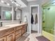 Bathroom with double sink vanity, two mirrors, and a shower with a green tile surround at 108 Parkridge Dr, Danville, IN 46122