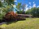 Rambling brick ranch on a sloping lot with a stained wood deck and stairs surrounded by mature trees at 108 Parkridge Dr, Danville, IN 46122