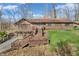 A multi-level brick house showcasing a wooden deck and stairs in a large yard with trees in early spring at 108 Parkridge Dr, Danville, IN 46122