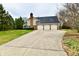 Spacious three-car garage with a long driveway, surrounded by lush greenery and mature trees at 12917 Brighton Ln, Carmel, IN 46032