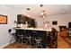 Basement wet bar area with dark cabinetry, light countertops, stainless steel appliances, and comfortable bar seating at 12917 Brighton Ln, Carmel, IN 46032