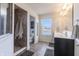 Modern bathroom with a tiled walk-in shower, double sink vanity, and large window overlooking the backyard at 12959 Balfour Rd, Fishers, IN 46037