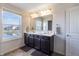 Bright bathroom featuring a double vanity with dark cabinets, large window, and tile flooring at 12959 Balfour Rd, Fishers, IN 46037