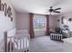 This cozy bedroom has pink walls, a ceiling fan, and a large window with neighborhood views at 12959 Balfour Rd, Fishers, IN 46037