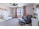 This cozy bedroom has pink walls, a ceiling fan, and a large window with neighborhood views at 12959 Balfour Rd, Fishers, IN 46037