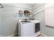 Bright laundry room features modern appliances, storage shelves, and neutral tile flooring at 12959 Balfour Rd, Fishers, IN 46037