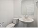 Modern half bathroom features a pedestal sink, toilet, and large mirror at 13752 N George Ct, Camby, IN 46113
