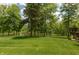 Expansive backyard featuring lush lawn, mature trees, and tranquil pond views from the property line at 1527 Canyon Oak Ln, Columbus, IN 47201