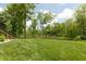 The backyard has a lush lawn with mature trees, with a view of the serene pond and natural surroundings at 1527 Canyon Oak Ln, Columbus, IN 47201