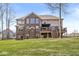 Back exterior showcasing a brick elevation, a deck, green grass, and a covered porch at 1527 Canyon Oak Ln, Columbus, IN 47201