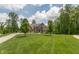 Beautiful brick home with lush green lawn, mature trees, and a long driveway on a sunny day at 1527 Canyon Oak Ln, Columbus, IN 47201