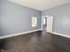 Empty bedroom with light blue walls, dark stained hardwood floors, and a window with a white blind at 1546 S New Jersey St, Indianapolis, IN 46225