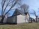 A single-story home showcasing gray vinyl siding and a black roof, situated next to a white vinyl privacy fence at 1546 S New Jersey St, Indianapolis, IN 46225