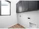 Bright laundry room featuring stylish dark cabinets with gold hardware and durable light wood-look floors at 17354 Newton Main St, Westfield, IN 46074