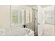 Bright bathroom with a soaking tub, shower, and window with shutter providing natural light and privacy at 2183 Glebe St, Carmel, IN 46032