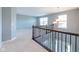 Open loft area with neutral carpet, iron railing, modern chandelier, and natural light from large window at 2314 Angelina Way, Greenwood, IN 46143
