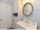 Bathroom with marble-topped vanity, round mirror, and storage cabinets at 2315 Cardinal Dr, Indianapolis, IN 46227