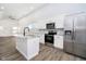 Open kitchen with stainless steel appliances, white cabinets, island with sink, and plank flooring at 238 N Tacoma Ave, Indianapolis, IN 46201