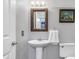 Clean bathroom with a white pedestal sink, toilet, and framed mirror, complemented by neutral walls at 3051 Arrow Wood Ln, Indianapolis, IN 46214